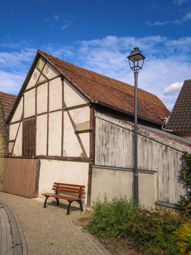 A vertical shot of an old house with a brick roof against a blue cloudy sky on a sunny day