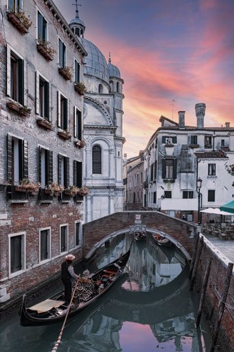 A vertical shot of a channel surrounded by buildings of Venice in Italy at sunset