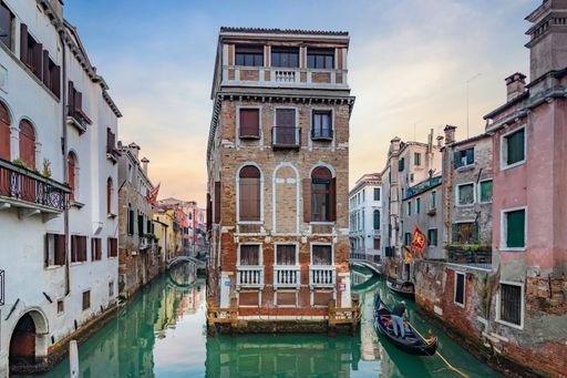 A scenery of a channel surrounded by buildings of Venice in Italy at sunset