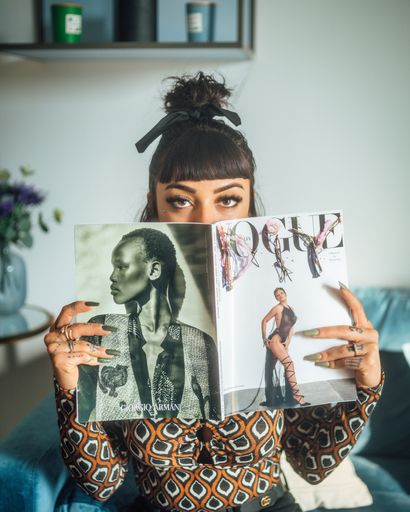 A beautiful Italian female looking over a Vogue Journal