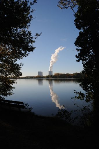 A cloud of smoke from the chimney from chemical plant and a reflection of it in a calm lake