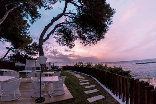 A beautiful shot of tables and chairs placed outside in front of the sea
