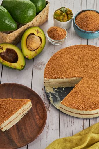 A closeup shot of slicing a piece of cake, avocados, and other ingredients