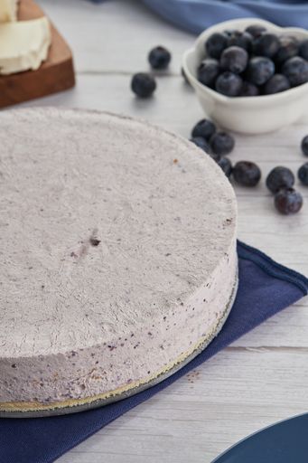 A vertical shot of a blueberry cream cake, berries, and other ingredients