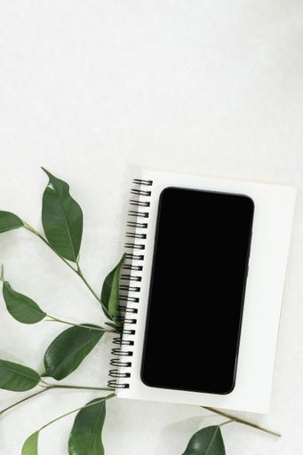 A spiral notebook and a smartphone on a white background