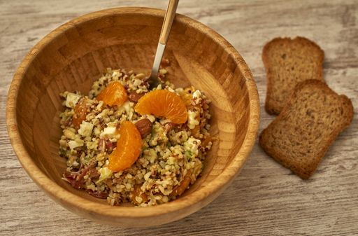 Top view of the quinoa salad with fresh tangerines on a wooden table