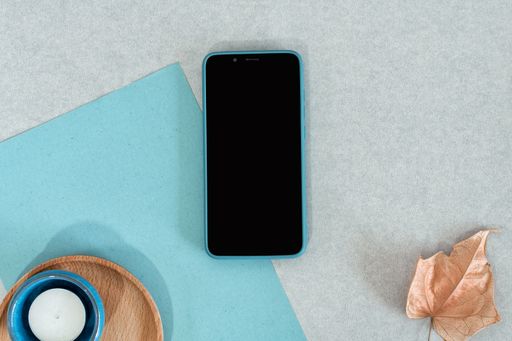 A top view of a smartphone with various decorative objects on a gray surface with space for text