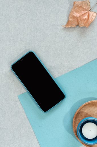 A top view of a smartphone with various decorative objects on a gray surface with space for text