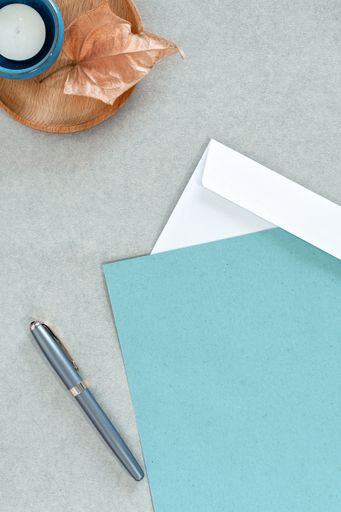 A top view of envelopes with a pen on a gray surface with space for text