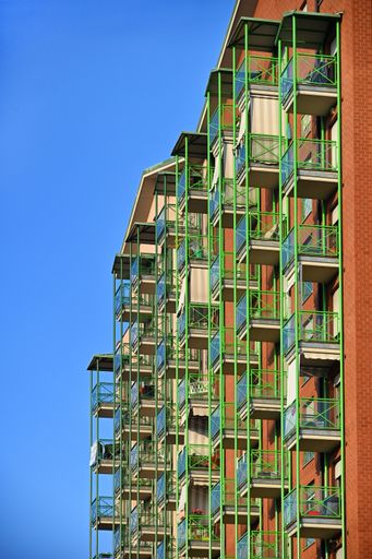 A vertical shot of a residential building balcony facade on blue sky