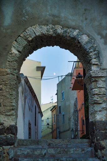 A vertical low angle view of a stone arch of an entrance of the ancient village in Sardinia