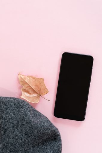 A top view of a smartphone on a pink surface with space for text