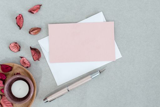 A top view of envelopes with a candle and autumn leaves on a gray surface with space text