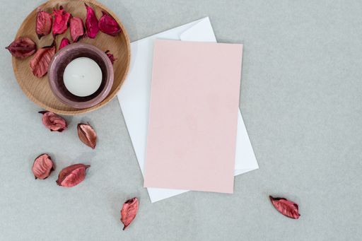 A top view of envelopes with a candle and autumn leaves on a gray surface with space text