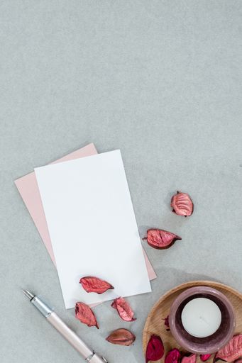 A top view of envelopes with a candle and autumn leaves on a gray surface with space text