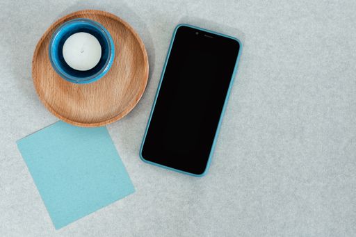 A top view of a smartphone with various decorative objects on a gray surface with space for text