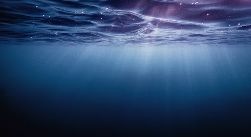 The dark blue ocean surface view from underwater with the rays of sunlight shining through