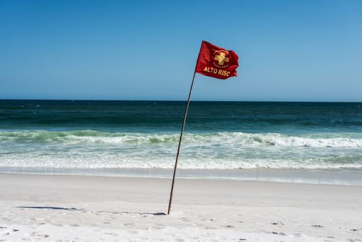 A beautiful view of a red flag on a sandy beach on a sunny day