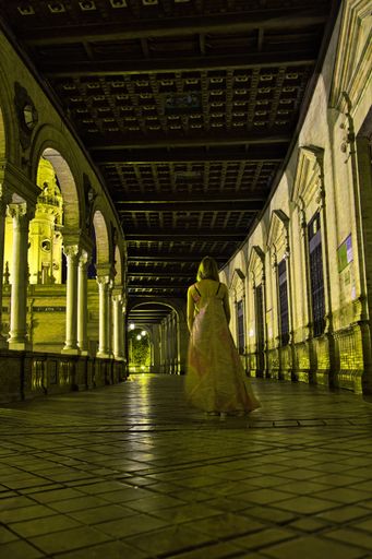 A vertical shot of the woman walking through the hallway. Plaza de Espana, Seville, Spain.