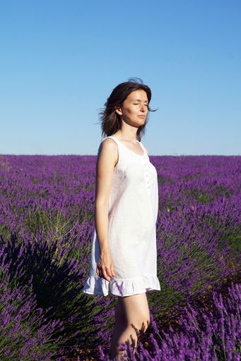 A scenic shot of a Caucasian short-haired woman wearing a white dress in a lavender field