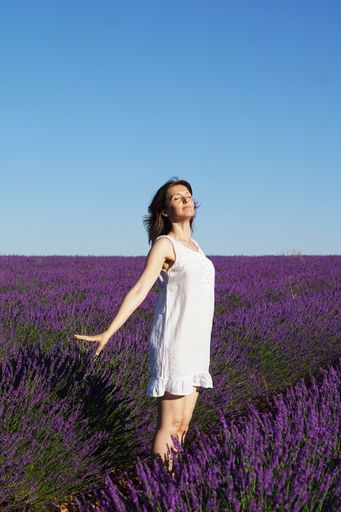 A scenic shot of a Caucasian short-haired woman wearing a white dress in a lavender field