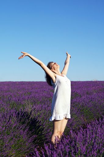 A scenic shot of a Caucasian short-haired woman wearing a white dress in a lavender field