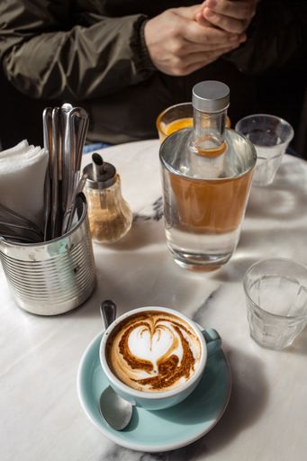 A beautiful vertical shot of a cappuccino and a table full of drinks