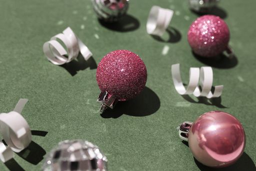 Festive composition with pink Christmas balls and white ribbons on the green surface