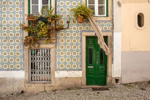 Traditional Portuguese house adorned with beautiful tiles, a colorful door, plants and laundry blowing in the wind.