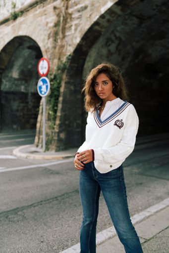 A vertical shot of an attractive Caucasian female in a white shirt and jeans posing on a street