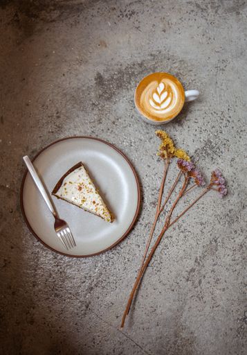 An overhead shot of cheesecake on the plate and cappuccino