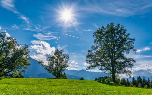 The blue sky over the green field and mountain range on a sunny day