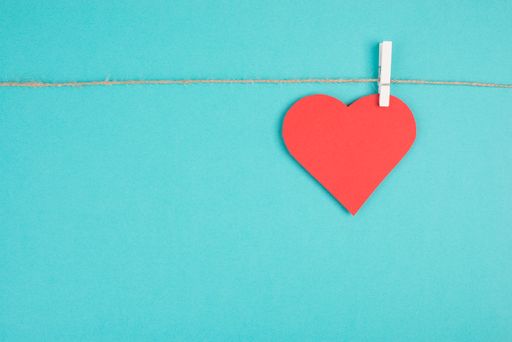 A heart hanging on a clothing line, blue colored background, empty copy space, symbol of love, valintine greeting card