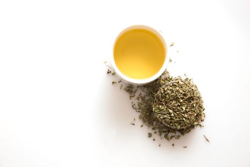 A top view of a cup of green tea and herbs isolated on a white background