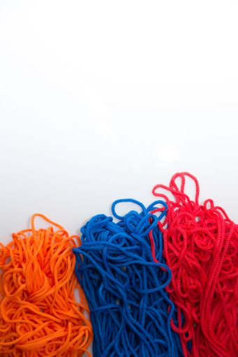 A vertical shot of red blue and orange threads creating the  Armenian flag on a white background