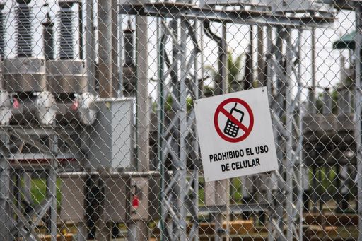 A shot of a factory and a sign attached to the fence. Translation: Cell phone use prohibited