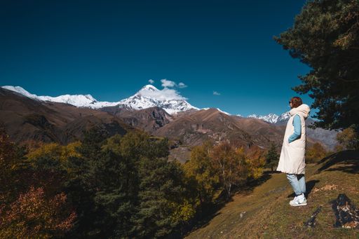 An adult Caucasian woman standing on a grassy hill and looking at snowy mountains in Ukraine