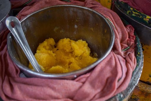 A high-angle shot of jaggery and a spoon in a metal plate
