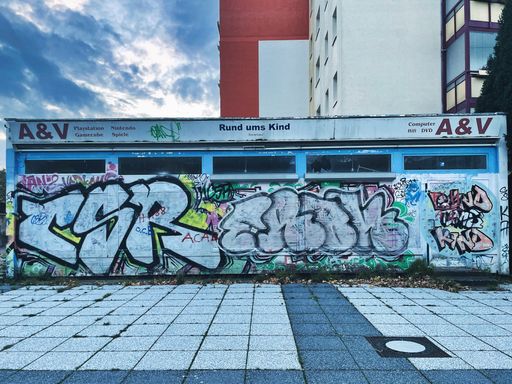 A graffiti on the wall of a vacant shop in Rostock under a blue cloudy sky