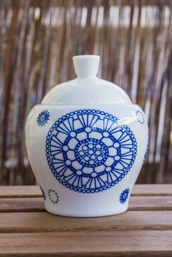 A close up shallow focus of a white ceramic ware with a decorated blue on a wooden table