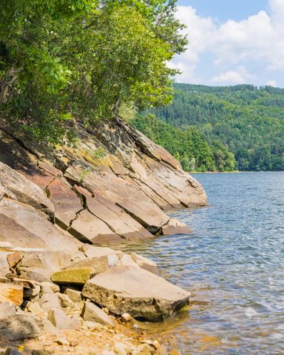Vertical shot of a rock looking like a sleeping dragon over Lake Zywieckie