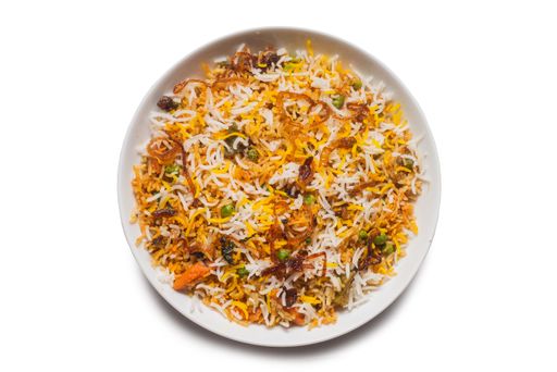A top view of biryani rice with vegetables on a white plate isolated on a white background