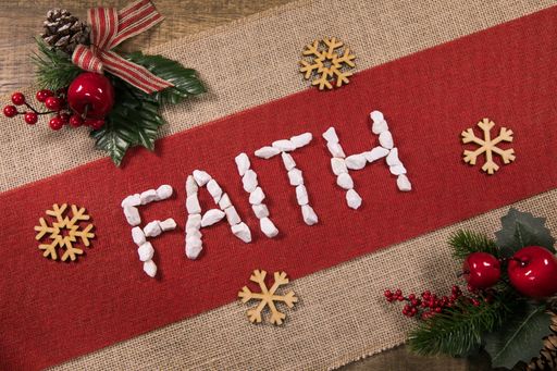 A top view of the "Faith" word with wooden snowflakes and pine decorations on a red linen fabric