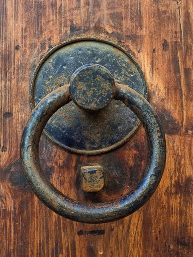 A vertical shot of an ancient metallic door knocker.