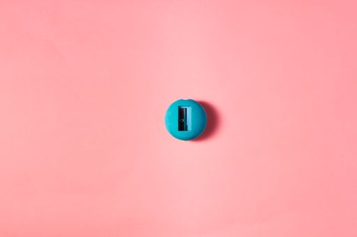 A top view of a blue small round pencil sharpener on the pink surface