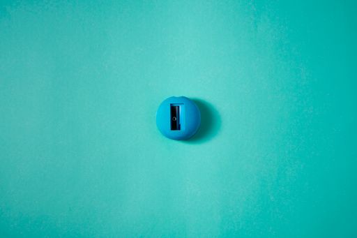 A top view of a blue small round pencil sharpener on the green surface