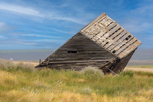 The abandoned wooden house in the field.