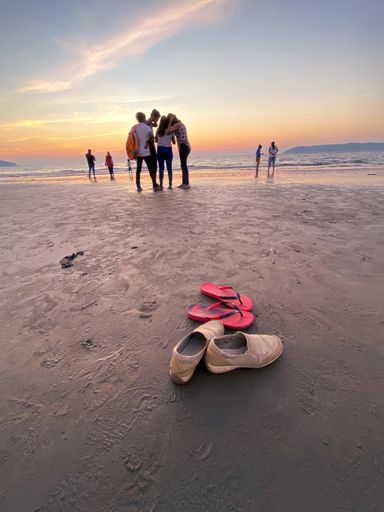 A vertical shot of people on the beach of Goa India at sunset