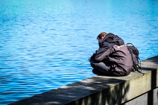 A male sitting on the wall at the edge of a lake in Hamburg, Germany
