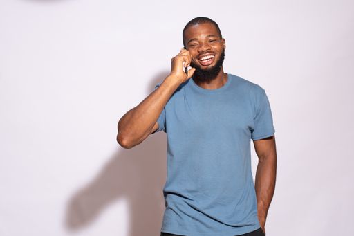 A smiling African male student standing against a white wall
